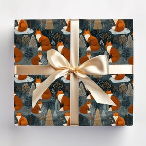 May include: Gift box wrapped in paper with a repeating pattern of foxes, trees, and clouds in shades of orange, white, and brown on a dark blue background. A gold ribbon and bow are tied around the box.