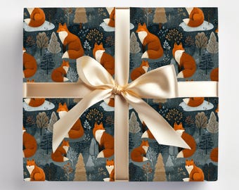 May include: Gift box wrapped in paper with a repeating pattern of foxes, trees, and clouds in shades of orange, white, and brown on a dark blue background. A gold ribbon and bow are tied around the box.