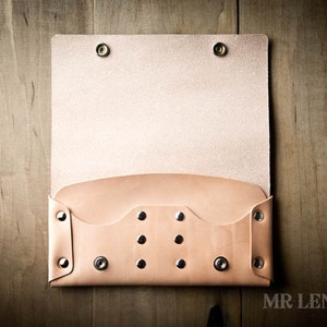 May include: A light brown leather wallet with a flap closure and multiple silver rivets. The wallet is open and the inside is visible.