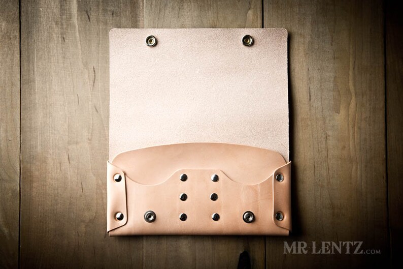 May include: A light brown leather wallet with a flap closure and multiple silver rivets. The wallet is open and the inside is visible.