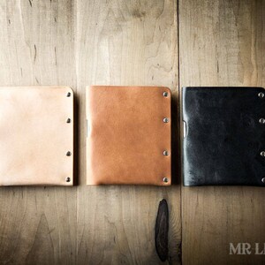 Pu&ograve; includere: Tre portafogli in pelle di diversi colori: beige, marrone e nero. Ogni portafoglio ha un design minimalista con una texture sottile e pi&ugrave; rivetti argentati.
