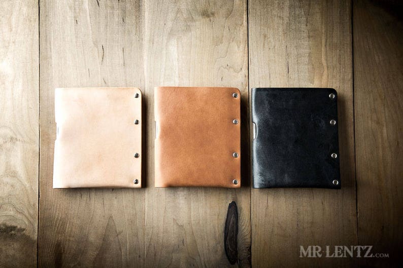Pu&ograve; includere: Tre portafogli in pelle di diversi colori: beige, marrone e nero. Ogni portafoglio ha un design minimalista con una texture sottile e pi&ugrave; rivetti argentati.