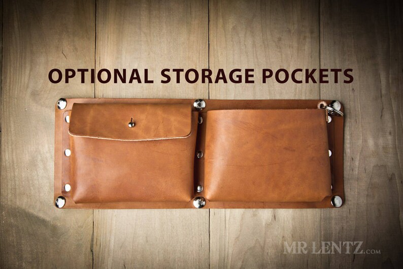 Pode incluir: Dois bolsos de armazenamento de couro castanho com rebites prateados e uma fivela prateada. Os bolsos est&atilde;o presos a um suporte de couro castanho. O texto "OPTIONAL STORAGE POCKETS" est&aacute; acima dos bolsos.