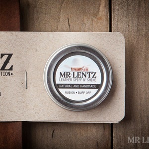 May include: A small silver tin with a white label that reads "MR. LENTZ Leather Spiff N' Shine Natural and Handmade Rub On Buff Off".
