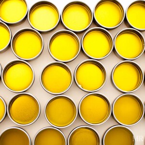 May include: A collection of small, round, yellow containers with silver lids. The containers are arranged in a grid pattern on a white surface.