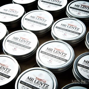 May include: Multiple silver tins of leather conditioner with the label "Mr. Lentz Leather Spiff 'n Shine - All Natural Old West Recipe".