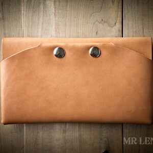 May include: A tan leather wallet with two silver snaps.