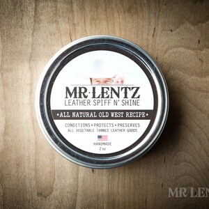 May include: A silver tin with a white label that reads "MR LENTZ LEATHER SPIFF N' SHINE &bull;ALL NATURAL OLD WEST RECIPE&bull; CONDITIONS PROTECTS PRESERVES ALL VEGETABLE TANNED LEATHER GOODS HANDMADE 2 oz"