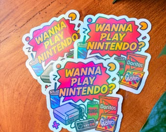 May include: A collection of holographic stickers with a retro gaming theme. Each sticker features the text "WANNA PLAY NINTENDO?" along with illustrations of a Nintendo console, snacks, and drinks. The stickers have a vibrant color scheme.