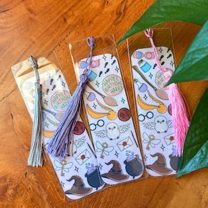 May include: Three clear plastic bookmarks with colorful illustrations and tassels. Each bookmark features images of a broom, owl, glasses, and the text "Happee Birthday Harry." The tassels are silver, purple, and pink.