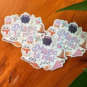 May include: A collection of whimsical stickers with a magical theme. Each sticker features illustrations of a cauldron, owl, key, potion bottle, witch hat, and the phrase "Magic is real" in a decorative font. The stickers are in shades of purple, pink, and brown.