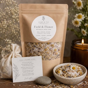 May include: A brown paper bag of "Field & Flower" botanical bath soak with daisy, oatstraw, lavender, chamomile, and sweet orange. A small muslin bag, a ceramic bowl, and a card with instructions are also present. A lit candle and a stone are also in the image.
