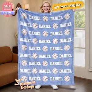Puede incluir: Una manta azul claro con un patrón repetido de pelotas de béisbol y el nombre "DANIEL" en blanco. La manta es mostrada por una persona. La imagen también incluye un banner de "SALE" y el texto "24 hours shipping".