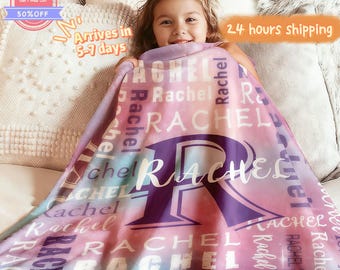 May include: A personalized blanket with the name "Rachel" in white lettering over a gradient of pink, purple, and blue. A large purple "R" is centered on the blanket. The blanket is soft and cozy.