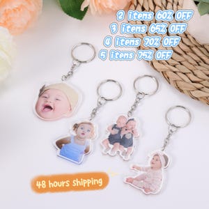 Op de afbeelding: Gepersonaliseerde sleutelhangers met babyfoto's. Elke sleutelhanger heeft een zilveren ring en ketting. De afbeelding bevat de tekst: "48 hours shipping" en "2 itens 60% OFF, 3 items 65% OFF, 4 items 70% OFF, 5 items 75% OFF."