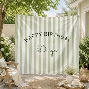 K&ouml;nnte beinhalten: Ein rechteckiger Stoffhintergrund mit vertikalen Streifen in Salbeigr&uuml;n und Wei&szlig;. Der Text "HAPPY BIRTHDAY" ist in einer dunkelgr&uuml;nen serifenlosen Schrift bogenf&ouml;rmig aufgedruckt, darunter steht der Name "Diego" in kursiver Schrift.