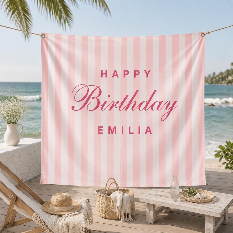 K&ouml;nnte beinhalten: Ein rechteckiger Stoffhintergrund mit vertikalen hellrosa und wei&szlig;en Streifen. Der Text "HAPPY" erscheint in einer fetten serifenlosen Schrift &uuml;ber dem Wort "Birthday" in Schreibschrift und dem Namen "EMILIA" in fetter serifenloser Schrift, alles in Rosa.