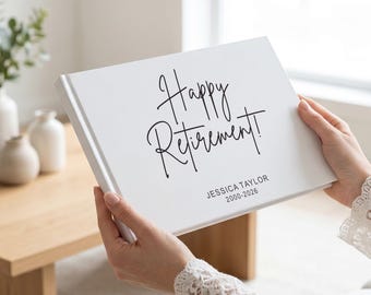 May include: A white rectangular book with black text on the front cover that reads Happy Retirement! followed by the name JESSICA TAYLOR and the years 2000-2026 in a clean sans-serif font. The book has a smooth matte finish and a hard cover.