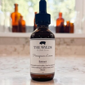 May include: A brown glass bottle with a black dropper, labeled "THE WYLDS" and "Homegrown Lemon Extract." The label mentions lemon peels and vodka for cooking. The bottle contains 2 fl oz.