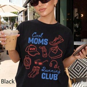 Peut inclure: T-shirt noir avec l'inscription "Cool Moms Running Club" en bleu et rouge. Le t-shirt présente des illustrations d'articles liés à la course, comme un chapeau, des chaussures et un casque. Le mot "Black" est imprimé en bas à gauche.