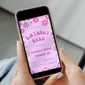 May include: A smartphone displays a birthday invitation with a retro floral design. The invitation reads "It's Time For A Birthday Bash Celebrating Hannah Grace Turning 10!" in pink and purple hues. The phone is held by a person with light blue nail polish.