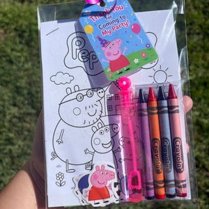 May include: A clear plastic party favour bag containing a Peppa Pig colouring sheet, four Crayola crayons in purple, orange, blue, and red, a small pink bubble wand, and a Peppa Pig sticker, topped with a blue thank you tag with a ribbon.