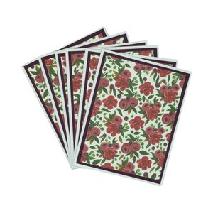 Puede incluir: Un conjunto de seis tarjetas con estampado floral. Cada tarjeta presenta un fondo blanco con un patrón repetido de rosas rojas y hojas verdes. Las tarjetas tienen un borde burdeos oscuro y están dispuestas en forma de abanico.
