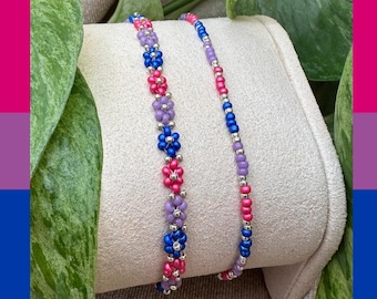 Könnte beinhalten: Ein Perlenarmband mit einem sich wiederholenden Muster aus kleinen Blumen aus rosa, violetten und blauen Saatperlen, durchsetzt mit metallisch silbernen Perlen. Das Design umfasst einen einzelnen Strang aus abwechselnden rosa, violetten und blauen Perlen.