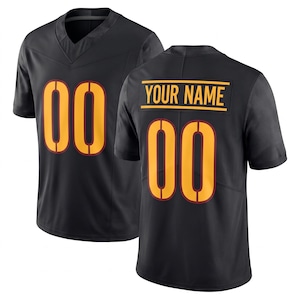 Op de afbeelding: Een zwart sportshirt met een V-hals en korte mouwen. De voorzijde toont het nummer 00 in het geel met een donkerrode omlijning. De achterzijde toont het nummer 00 en een geel rechthoekig naamplaatje met de tekst YOUR NAME.