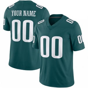 May include: A dark teal short-sleeved jersey featuring white numbers 00 on the front and back, with the text YOUR NAME printed in white on the back. The jersey has a V-neck collar and white accents on the shoulders and sleeves, displaying a clean design.