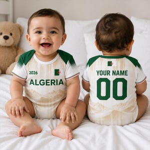 May include: A baby bodysuit featuring the Algeria flag, the text ALGERIA, the year 2026, and a desert landscape print. The back displays the text YOUR NAME and the number 00. The garment has green sleeves with a white and green gradient pattern.