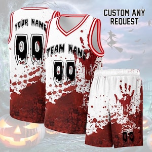 Peut inclure: Un ensemble de maillot et short de basket-ball blanc avec un motif d'éclaboussures de sang rouge. Le maillot affiche le texte YOUR NAME et TEAM NAME avec le numéro 00 dans une police noire dégoulinante. Le short présente une empreinte rouge.
