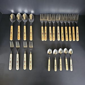 May include: A flatware set consisting of four large spoons, four large forks, nine small forks, and five small spoons. Each piece features a polished stainless steel head and a cream-colored handle decorated with a repeating geometric pattern.