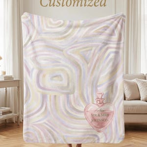 May include: A soft, pastel-colored blanket with a swirling pattern. The blanket features a heart-shaped perfume bottle design with the text "New MR & MRS JOHNSON". The word "Customized" is written at the top.