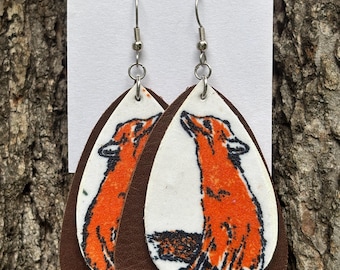 Peut inclure: Boucles d'oreilles en forme de goutte composées d'une couche blanche avec une illustration de renard orange et d'une couche arrière marron foncé. Elles sont suspendues à des crochets en métal argenté sur un support blanc THRIFTY MARE EARRINGS.
