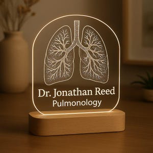 May include: A light-up acrylic plaque featuring a detailed lung illustration, mounted on a wooden base. The text "Dr. Jonathan Reed Pulmonology" is displayed beneath the lung graphic. The light emits a warm glow.