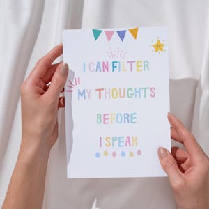Puede incluir: Una tarjeta blanca con el texto "I CAN FILTER MY THOUGHTS BEFORE I SPEAK" en colores pastel. La tarjeta est&aacute; decorada con banderas coloridas, una estrella y otras peque&ntilde;as ilustraciones. La tarjeta est&aacute; sostenida por dos manos.