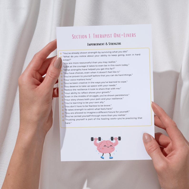 May include: A white paper with text titled "SECTION 1: THERAPIST ONE-LINERS" and "EMPOWERMENT & STRENGTHS". The paper has a cartoon brain lifting weights. The paper is held by two hands.