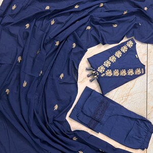 May include: A navy blue three-piece outfit featuring a long, flowing scarf, a sleeveless top, and pants. The top and pants have gold floral embroidery. The scarf is scattered with gold leaf-shaped embroidery. The pants have a decorative lace trim.