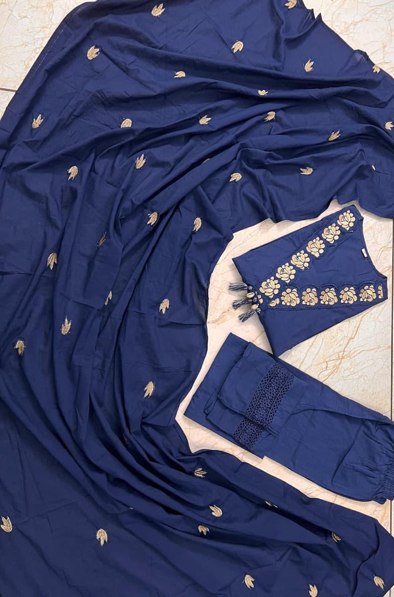 May include: A navy blue three-piece outfit featuring a top, pants, and a draped fabric. The top and pants have gold embroidery. The top has a floral design around the neckline and tassels. The pants have a lace trim.