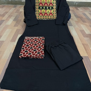 Puede incluir: Un conjunto de kurta negro con una parte superior de manga larga con un canes&uacute; bordado en rojo, amarillo y verde. El conjunto incluye pantalones negros a juego y una bufanda estampada en rojo y negro.
