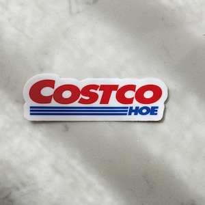 May include: A white sticker with the word "Costco" in red, and the word "HOE" in blue. The sticker has a white border and is on a white surface.