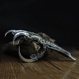 May include: A white ceramic mug with a black handle and the text "But First, Coffee" in a bold, black font. The mug is on a wooden surface. The mug is approximately 10 cm tall.