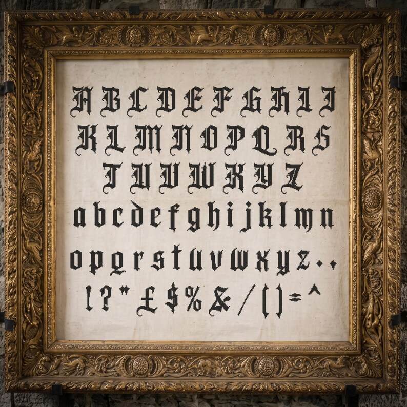 May include: A framed sampler featuring black embroidered gothic-style letters, numbers, and symbols on a light beige fabric background. The ornate, rectangular gold frame has intricate relief carvings of foliage and figures along its border.