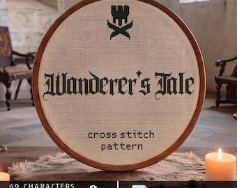 Op de afbeelding: Een ronde houten borduurring met beige stof en zwarte kruissteekborduurwerk. De tekst luidt Wanderer's Tale, cross stitch pattern, met een kasteelpictogram. Daaronder staat de specificatie 69 characters, 49-55 st high, Aida 14/16/18 voor het patroon.