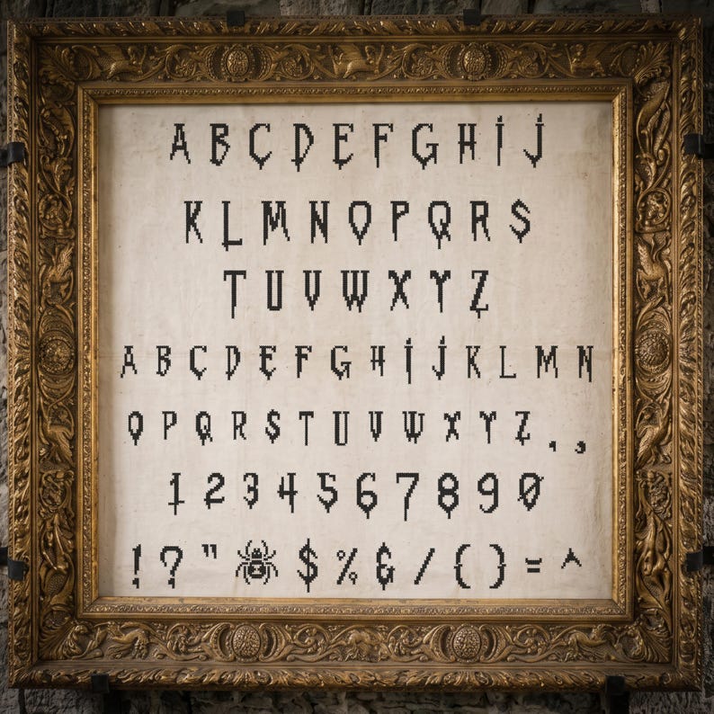 May include: A cross-stitch alphabet pattern on off-white fabric featuring black letters, numbers, and symbols with a dripping effect, displayed in an ornate, rectangular gold-colored frame with intricate relief carvings along the border.