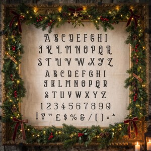 May include: A cross-stitch alphabet sampler on light fabric featuring uppercase letters A through Z, numbers 0 through 9, and various punctuation marks in black thread, framed by a decorative garland with pine needles, red berries, and lights.