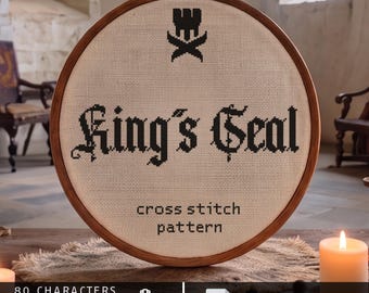 Op de afbeelding: Een ronde houten borduurring met een kruissteekpatroon op gebroken wit doek. Het ontwerp toont een zwart kroonicoon boven de tekst King's Seal en de woorden cross stitch pattern. De tekst onderaan bevat 80 characters, 40-47 st high, Aida 14/16/18 en digital download.