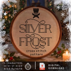 May include: A circular wooden embroidery hoop containing a cross stitch pattern on beige fabric. The design features a black crown icon above the text SILVER FROST and the words cross stitch pattern. Text at the bottom reads 75 CHARACTERS, 11-51 ST HIGH, AIDA 14/16/18.