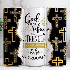 May include: A white tumbler featuring the text "God is our refuge and strength, an ever-present help in trouble." The sides of the tumbler have a black and gold cross pattern.